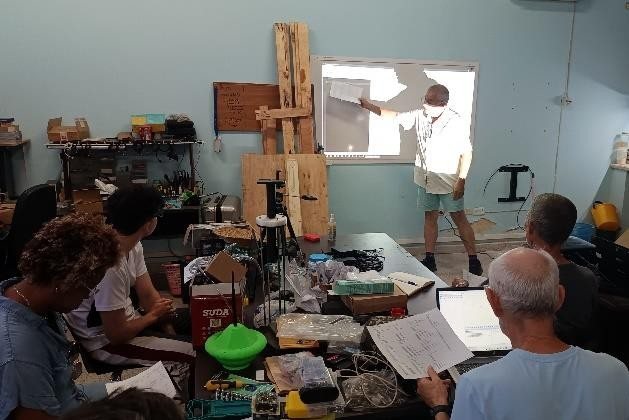 Microtaller: sesión de explicación frente a la pizarra, con prototipos y materiales sobre las mesas.