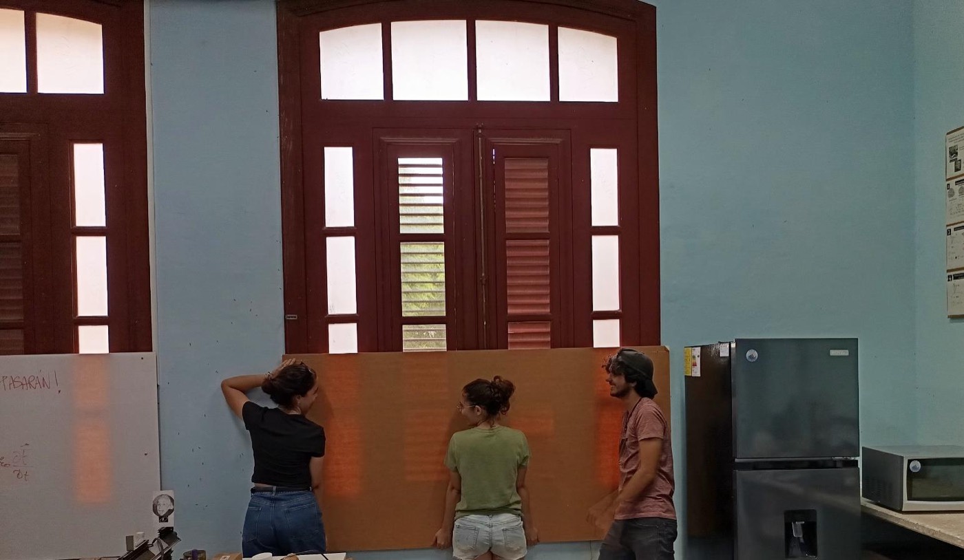 Estudiantes del proyecto tapiando con acrílico una ventana vulnerable del edificio de Física.